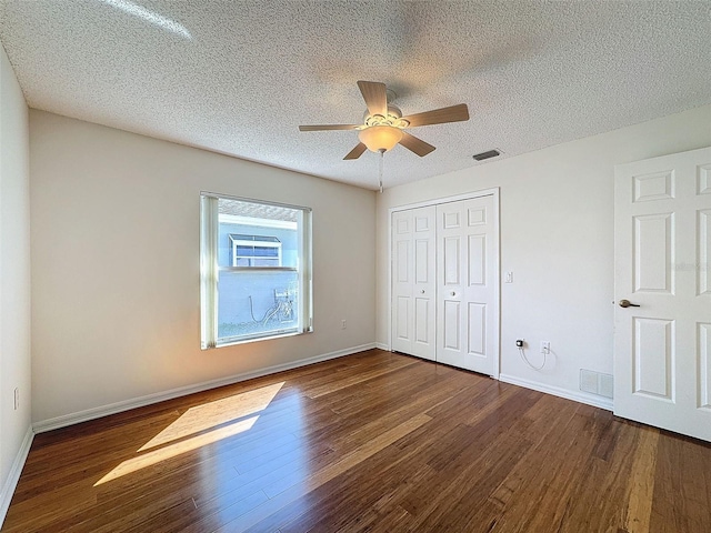 unfurnished bedroom featuring baseboards, visible vents, wood finished floors, a textured ceiling, and a closet