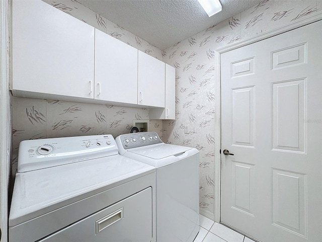 washroom featuring a textured ceiling, independent washer and dryer, cabinet space, and wallpapered walls