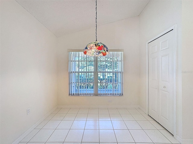 unfurnished dining area with light tile patterned floors, baseboards, and vaulted ceiling