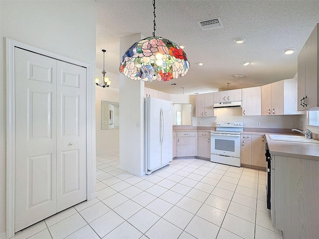 kitchen with white appliances, under cabinet range hood, a sink, and light tile patterned flooring