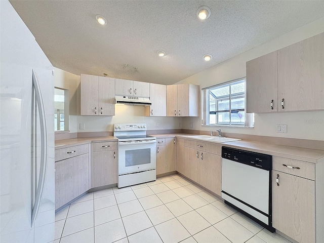 kitchen featuring white appliances, light countertops, a textured ceiling, under cabinet range hood, and a sink