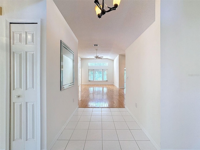 hallway featuring a textured ceiling, light tile patterned flooring, visible vents, and baseboards