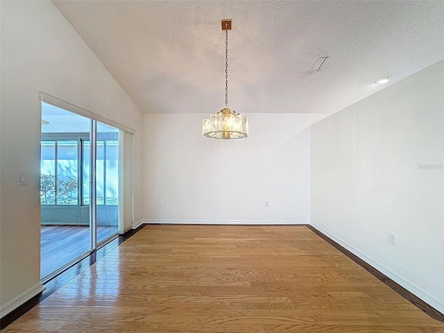 empty room featuring baseboards, wood finished floors, visible vents, and a notable chandelier