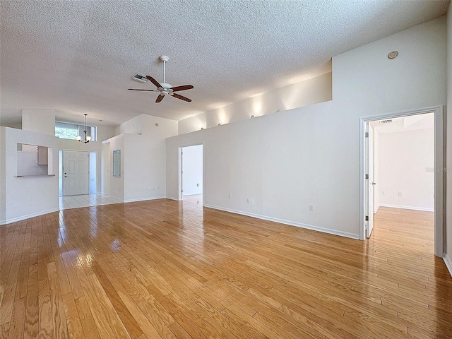 empty room with light wood-type flooring, visible vents, a textured ceiling, and ceiling fan with notable chandelier