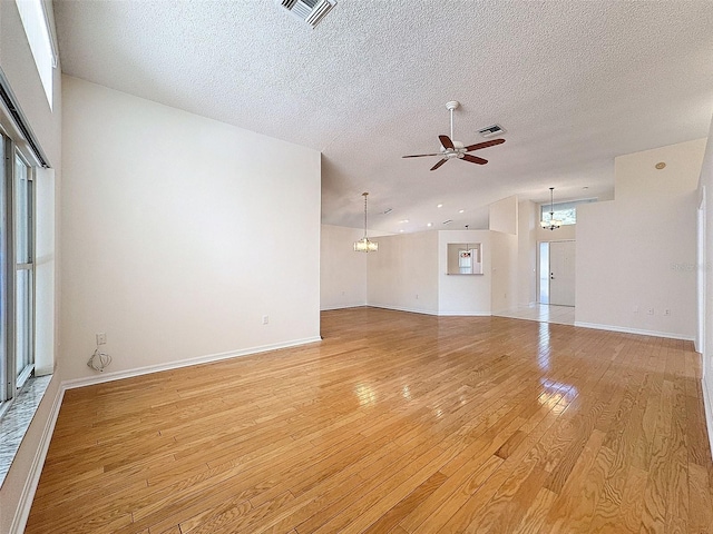 unfurnished living room featuring lofted ceiling, light wood-style floors, visible vents, and ceiling fan with notable chandelier