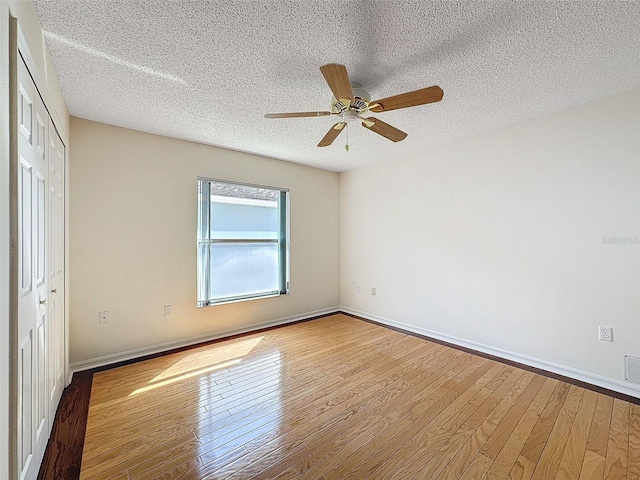 unfurnished bedroom with a closet, a textured ceiling, baseboards, and hardwood / wood-style flooring