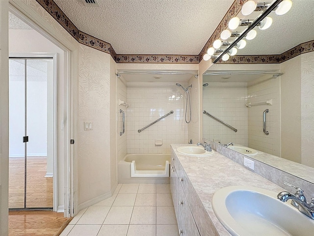 full bathroom featuring a textured ceiling, tile patterned flooring, and a sink