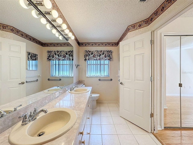 full bath with a textured ceiling, a sink, and toilet