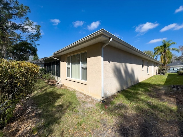 view of side of property with a lawn and stucco siding