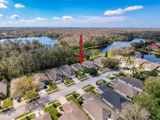 drone / aerial view with a residential view, a water view, and a view of trees