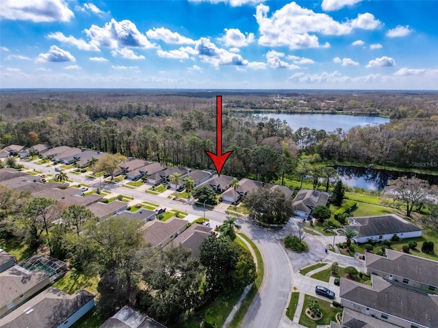 drone / aerial view featuring a residential view, a water view, and a view of trees