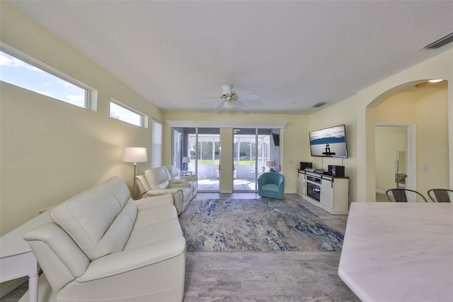 living room with visible vents, arched walkways, a ceiling fan, and wood finished floors