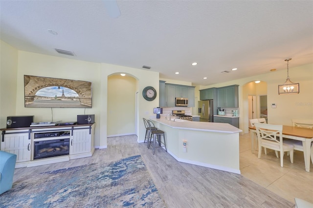 kitchen featuring arched walkways, light countertops, visible vents, appliances with stainless steel finishes, and a peninsula