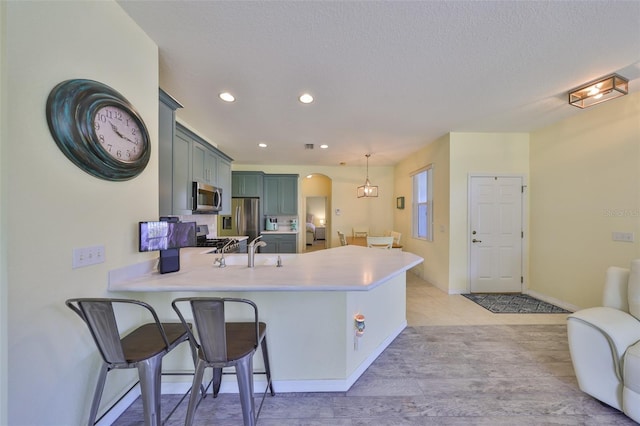 kitchen with stainless steel appliances, arched walkways, light countertops, and a peninsula