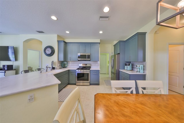 kitchen with stainless steel appliances, arched walkways, visible vents, and a sink