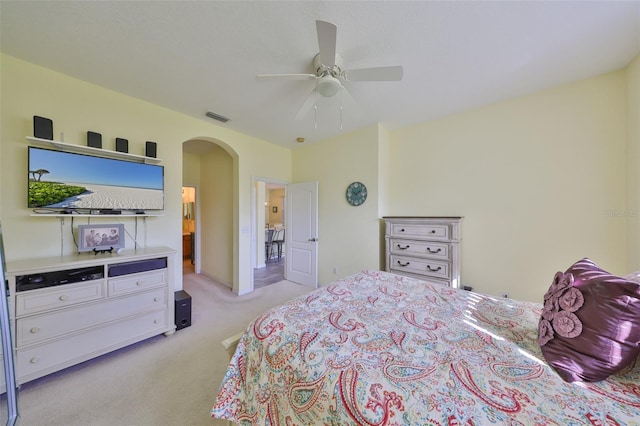 bedroom featuring light colored carpet, arched walkways, visible vents, and ceiling fan