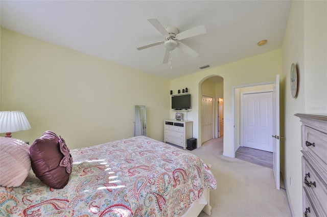 bedroom featuring light colored carpet, arched walkways, visible vents, and ceiling fan