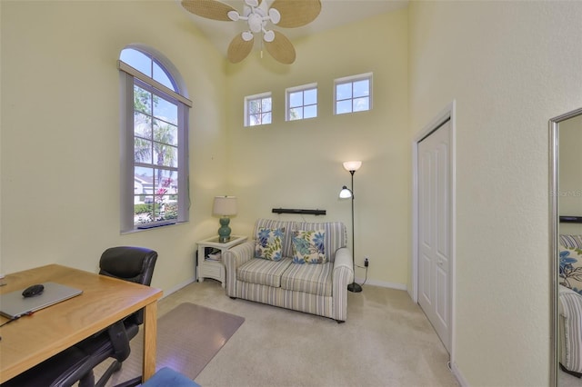 carpeted home office featuring ceiling fan, a high ceiling, and baseboards