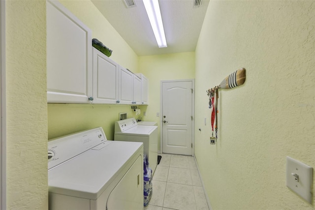 clothes washing area featuring cabinet space, washing machine and dryer, light tile patterned floors, and visible vents