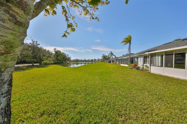 view of yard featuring a sunroom and a water view