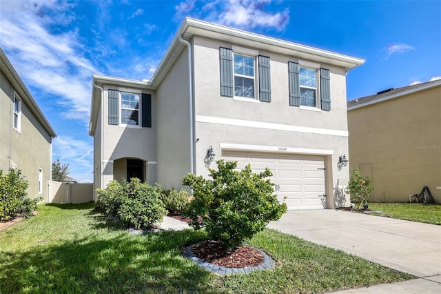 traditional home featuring driveway, a garage, a front lawn, and stucco siding