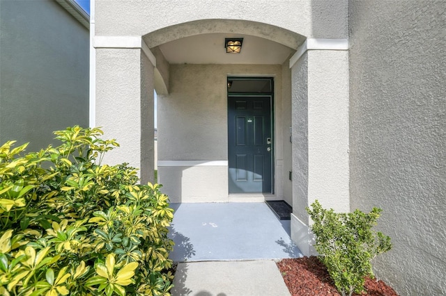 doorway to property featuring stucco siding