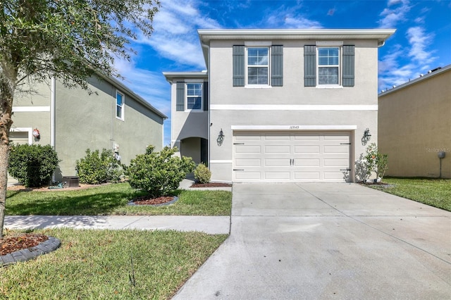 view of front of property featuring driveway, an attached garage, a front lawn, and stucco siding