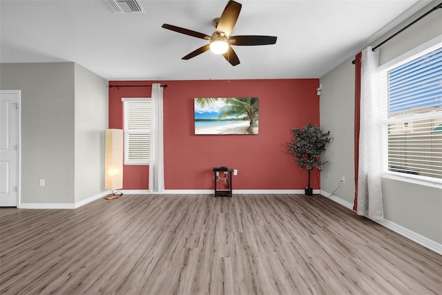 empty room with a ceiling fan, baseboards, visible vents, and wood finished floors