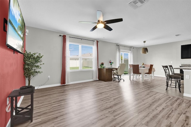 interior space featuring light wood-style floors, baseboards, visible vents, and a ceiling fan