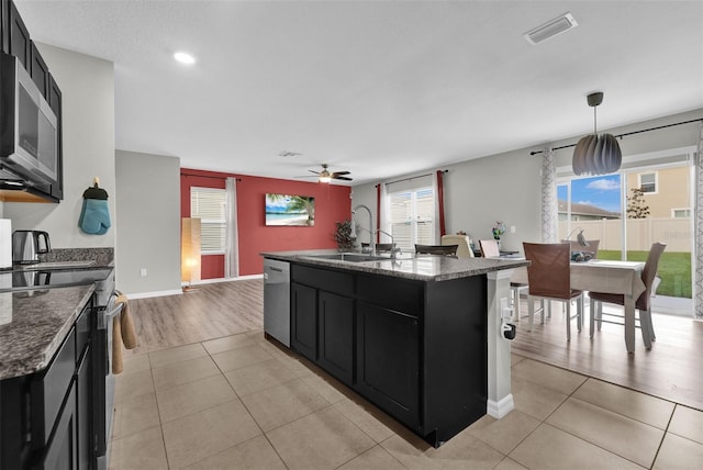 kitchen featuring visible vents, appliances with stainless steel finishes, dark cabinets, a sink, and light tile patterned flooring