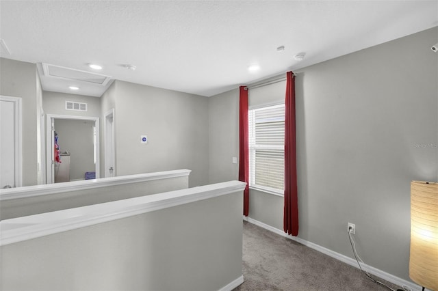 hall featuring attic access, visible vents, baseboards, an upstairs landing, and carpet floors