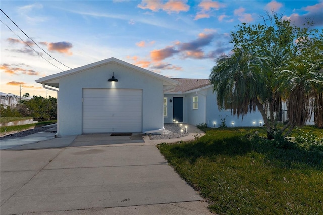 ranch-style house with a garage, driveway, and stucco siding