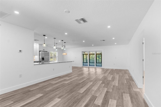 unfurnished living room featuring baseboards, light wood finished floors, visible vents, and recessed lighting