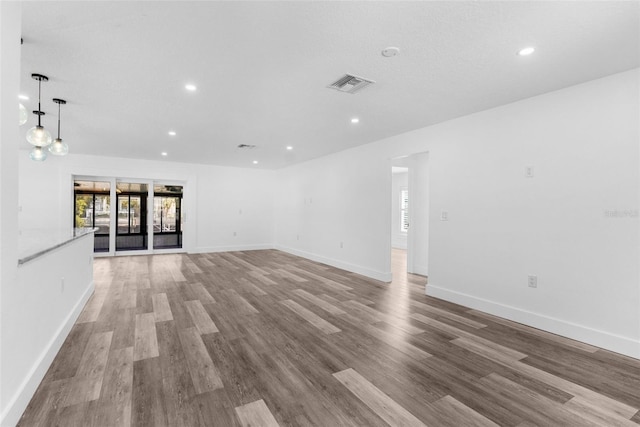 unfurnished living room featuring baseboards, visible vents, wood finished floors, and recessed lighting