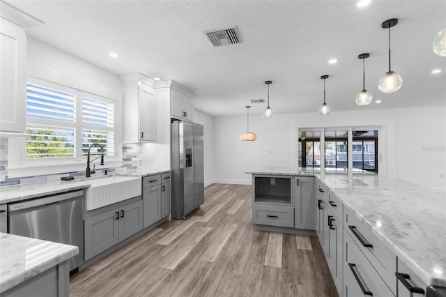 kitchen with visible vents, stainless steel appliances, a sink, and gray cabinetry