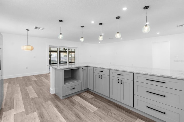 kitchen featuring light wood-style flooring, visible vents, light stone counters, and gray cabinetry