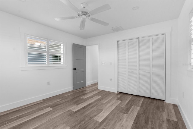 unfurnished bedroom featuring a ceiling fan, a closet, baseboards, and wood finished floors