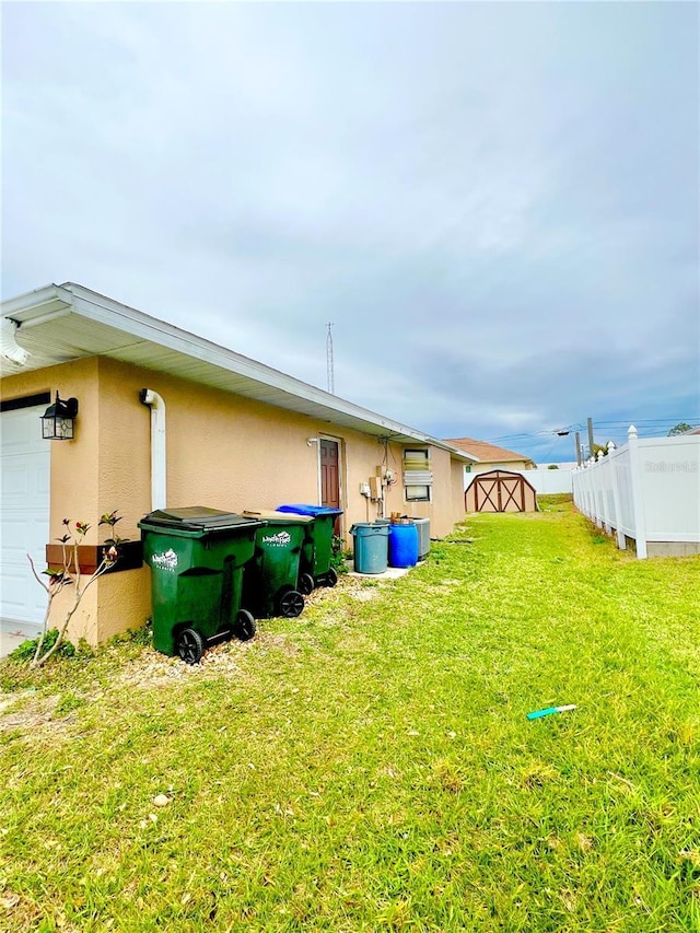 view of yard featuring a garage, fence, and an outdoor structure