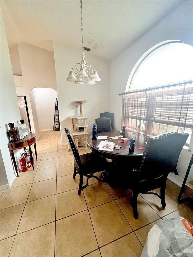 dining room with arched walkways, light tile patterned flooring, baseboards, vaulted ceiling, and an inviting chandelier