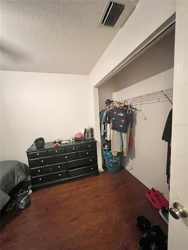 bedroom featuring visible vents, a textured ceiling, and wood finished floors