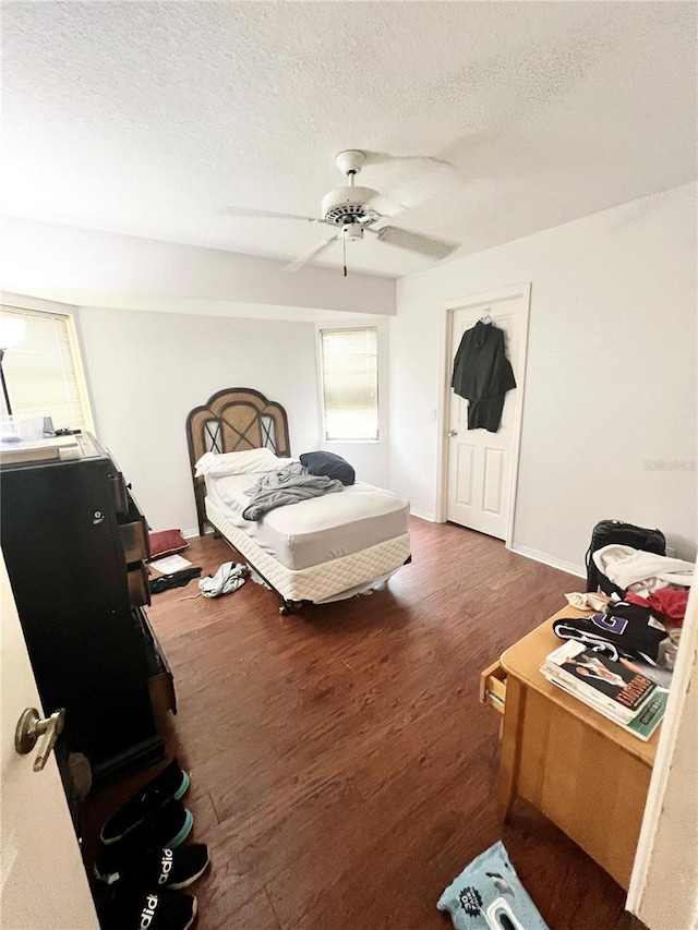 bedroom featuring a textured ceiling, wood finished floors, a ceiling fan, and baseboards