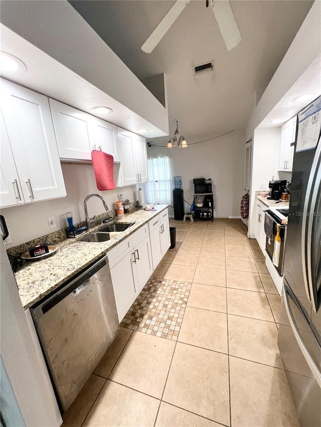 kitchen with light tile patterned flooring, a sink, white cabinetry, appliances with stainless steel finishes, and light stone countertops