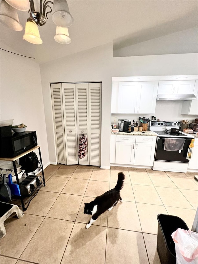 kitchen featuring light tile patterned floors, range with electric stovetop, vaulted ceiling, and black microwave