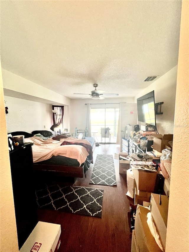 bedroom with access to exterior, a textured ceiling, visible vents, and wood finished floors