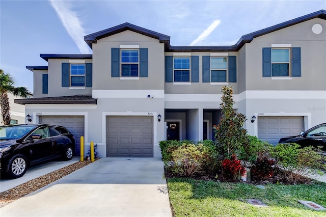 townhome / multi-family property with a garage, concrete driveway, and stucco siding