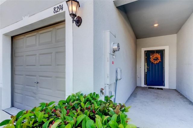 property entrance featuring a garage and stucco siding