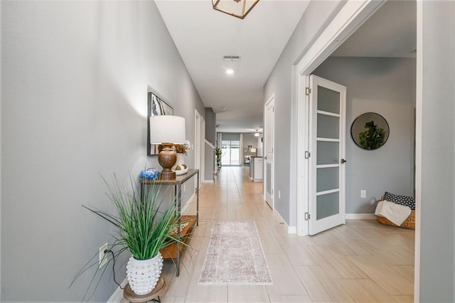 hall featuring visible vents and baseboards