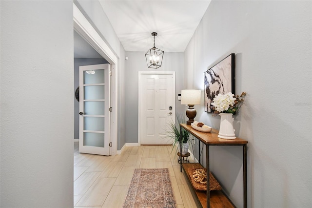 entryway with baseboards, an inviting chandelier, and light wood finished floors