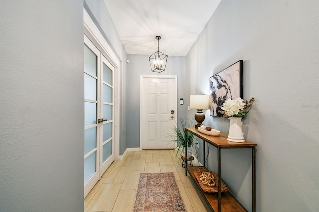 doorway with light wood-style flooring, a notable chandelier, and baseboards