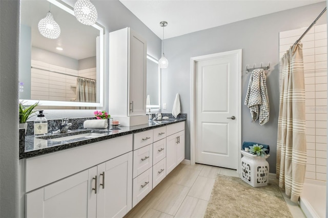 bathroom with a tile shower, double vanity, and a sink